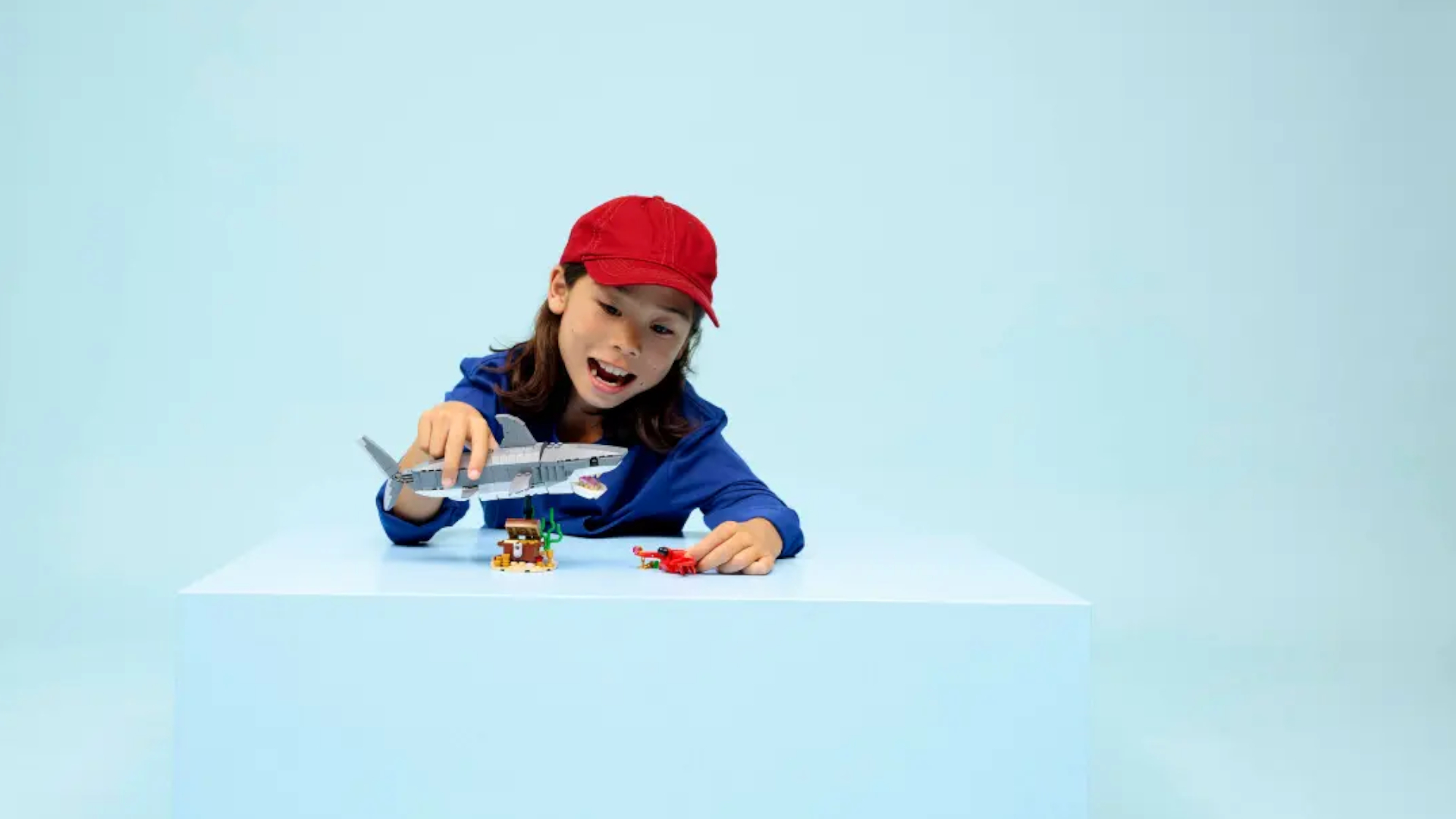 A child plays with a Lego shark in a blue area