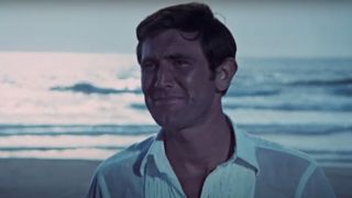 George Lazenby smiles on the beach in On Her Majesty's Secret Service