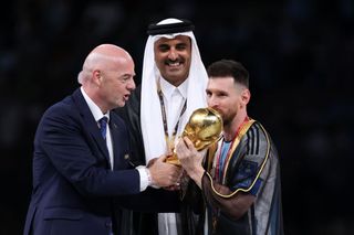 Lionel Messi of Argentina kisses the FIFA World Cup Qatar 2022 Winner's Trophy as Gianni Infantino, President of FIFA, and Sheikh Tamim bin Hamad Al Thani, Emir of Qatar, look on during the FIFA World Cup Qatar 2022 Final match between Argentina and France at Lusail Stadium on December 18, 2022 in Lusail City, Qatar.
