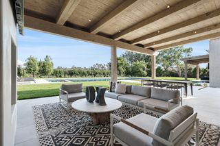 outdoor living space with wooden beamed covering, grey outdoor furniture, rug, coffee table