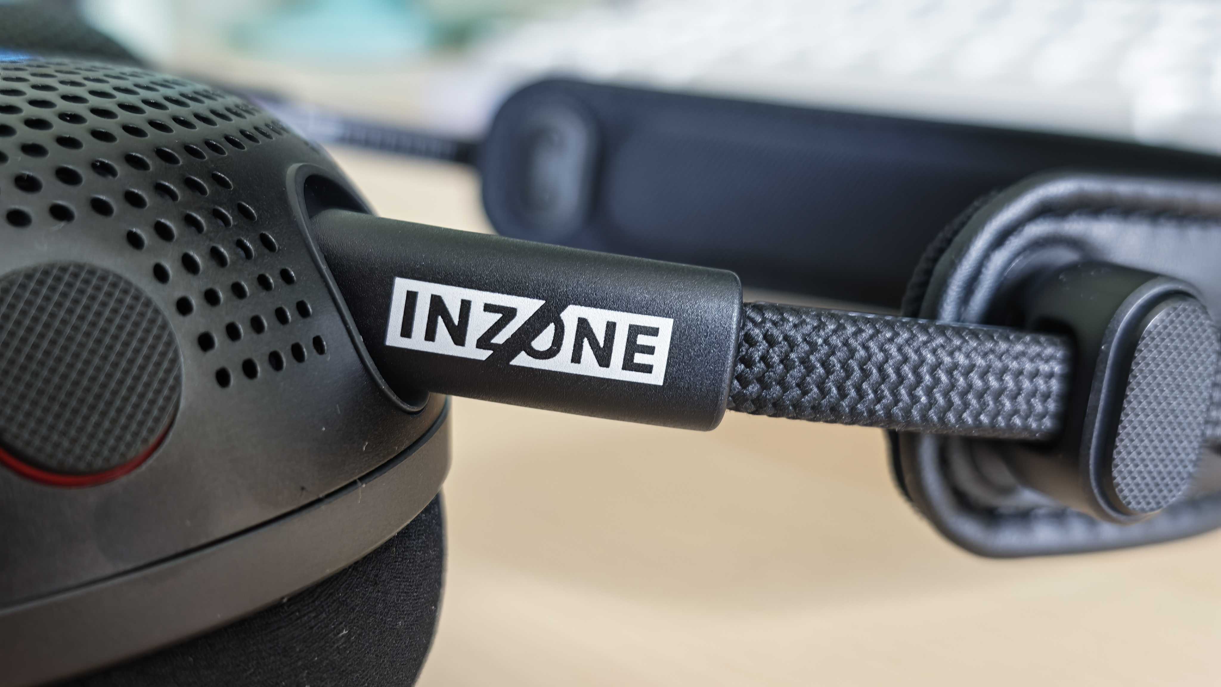 A photo of the Inzone H6 Air gaming headset positioned above a wooden desktop surface.