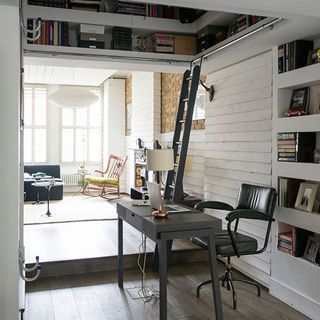 home office with book shelves and ladder with desk and chair
