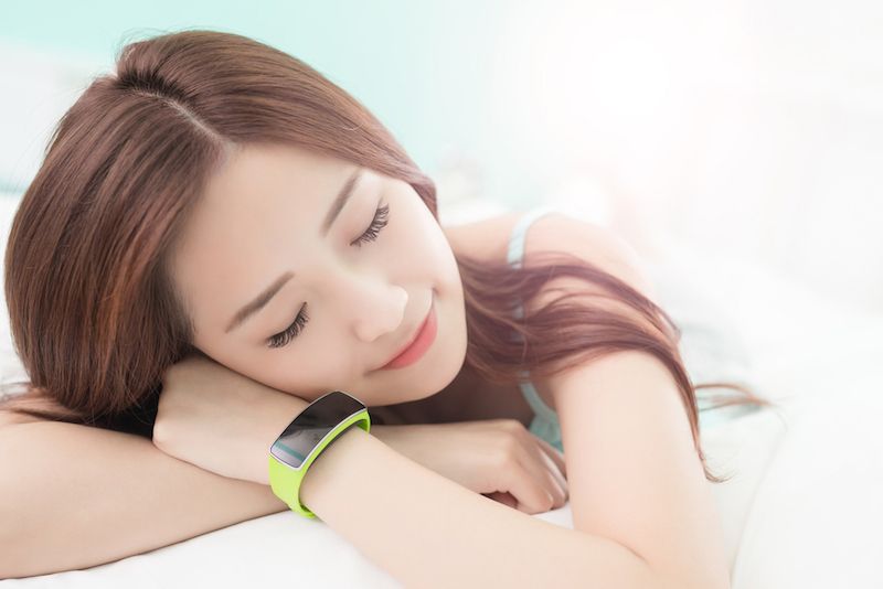 A woman snoozes while wearing a fitness tracker