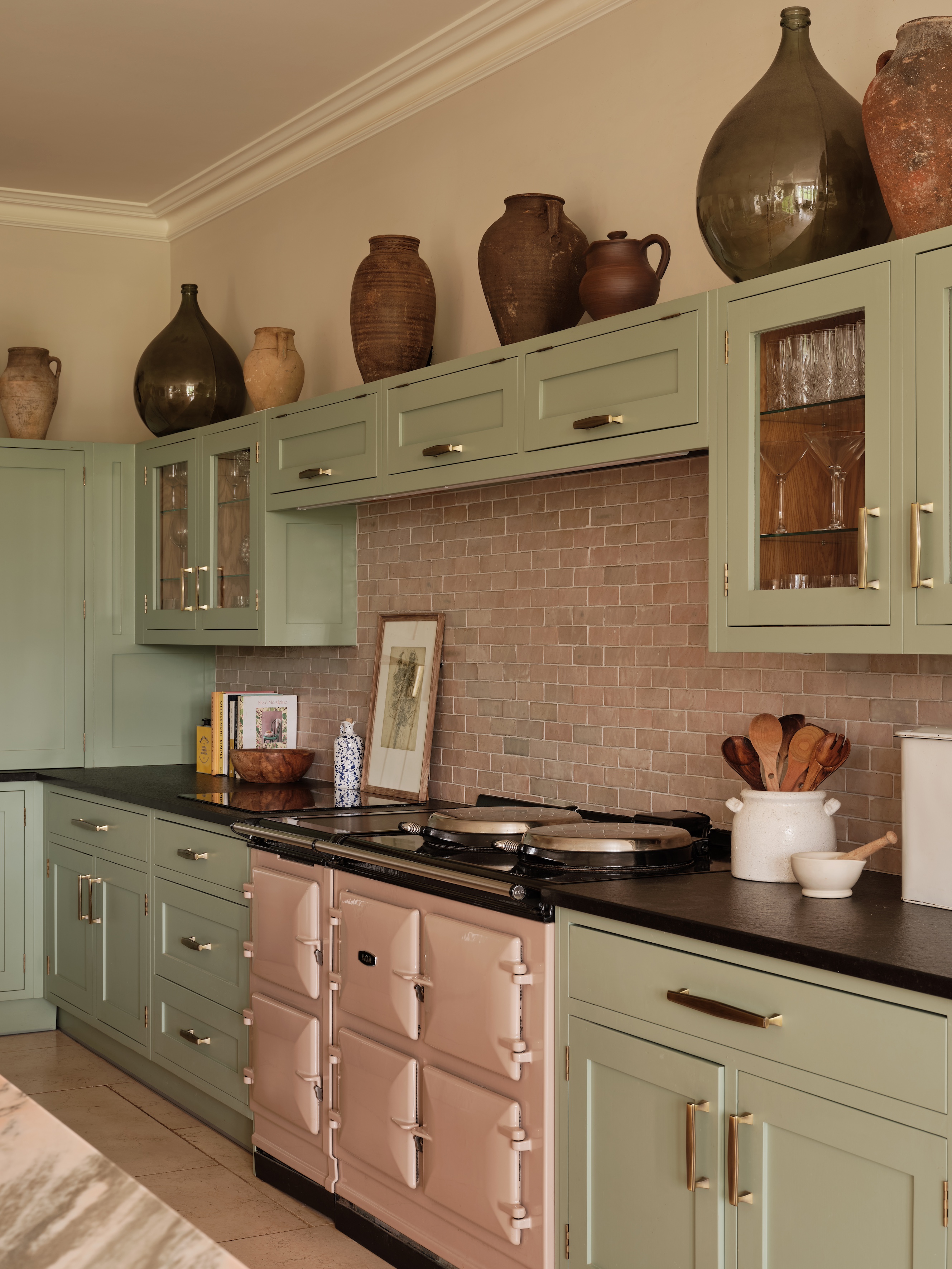sage green kitchen with terracotta brick backsplash and a pink range oven