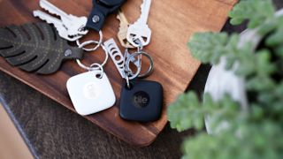 A black and white Tile Mate Bluetooth tracker attached to different sets of keys