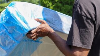 A man places a plastic-covered mattress into a van for moving to a new house