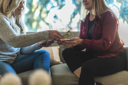 woman handing money to aniother woman