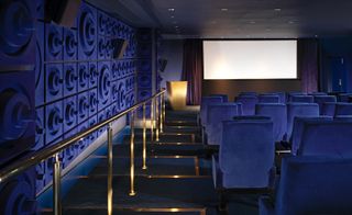 The cinema in the Sea Containers hotel. Dark blue sitting and walls, with golden railing in between, and the screen of the far wall.