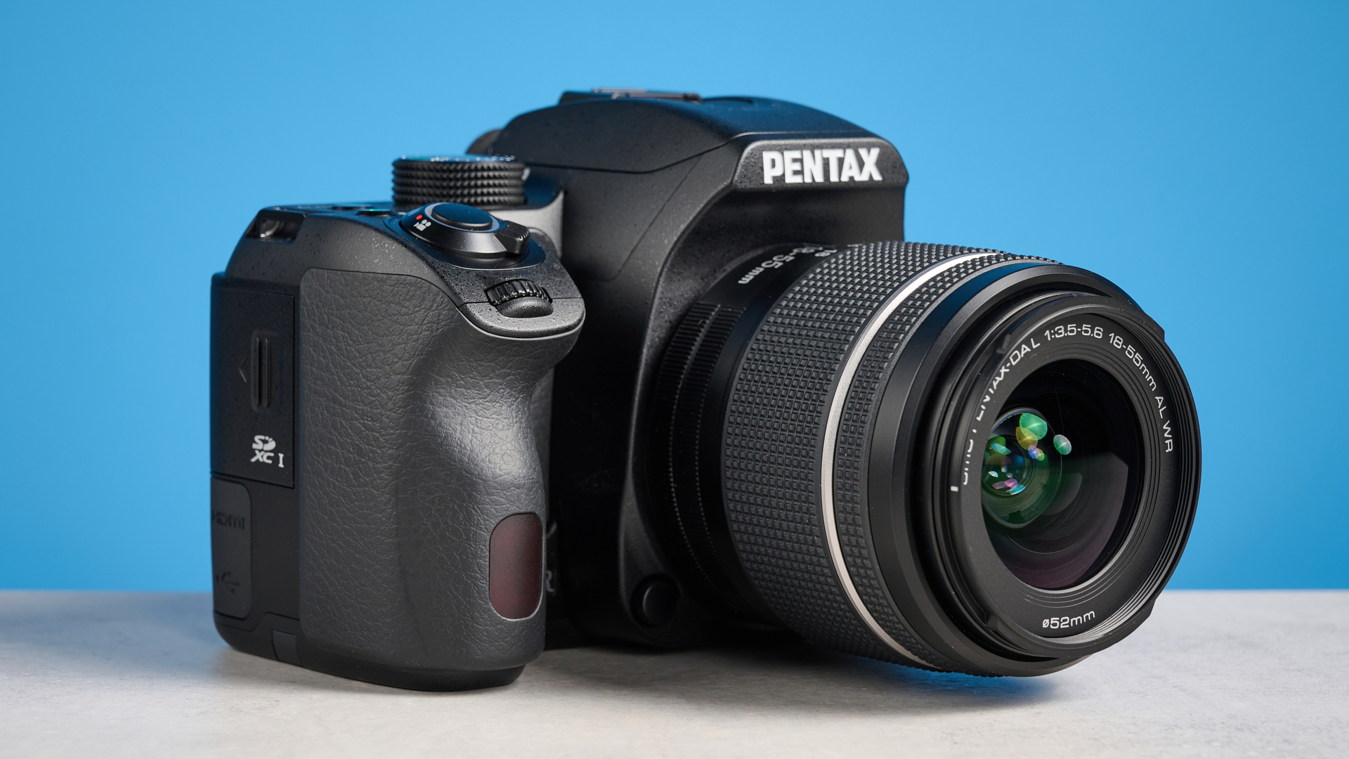 Pentax KF DSLR camera photographed on a blue background