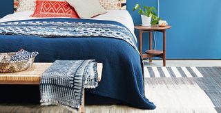 Blue bedroom with blue bedlinen on the bed and a warming rug beside the bed to make the room cosy