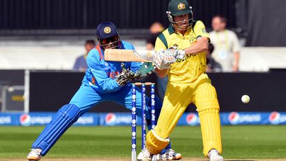 Australia's Adam Voges (R) plays a shot as India's captain wicketkeeper Mahendra Singh Dhoni looks on during the warm-up cricket match ahead of the 2013 ICC Champions Trophy between India and