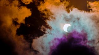 solar eclipse April 2023: Partial annular solar eclipse, known in such circumstances as a ring of fire, seen in Malaysia in 26th Dec 2019. Cloudy weather in the Kuala Lumpur obscuring much of the view. Dramatic colour applied.