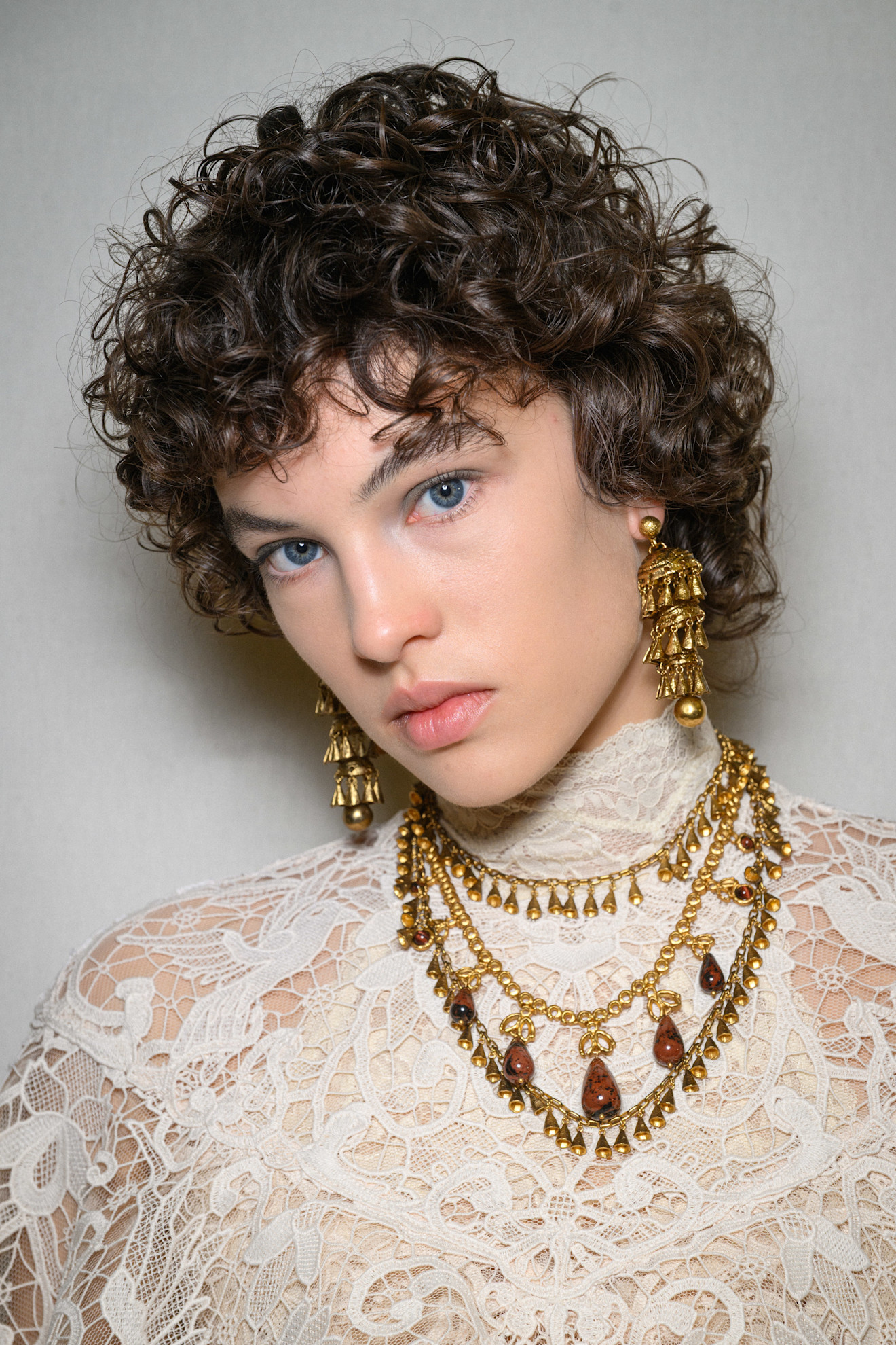 A model showing off her curly bixie cut with a lace top