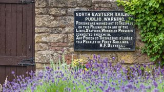 Lavender beds in front of old stone wall with railway sign