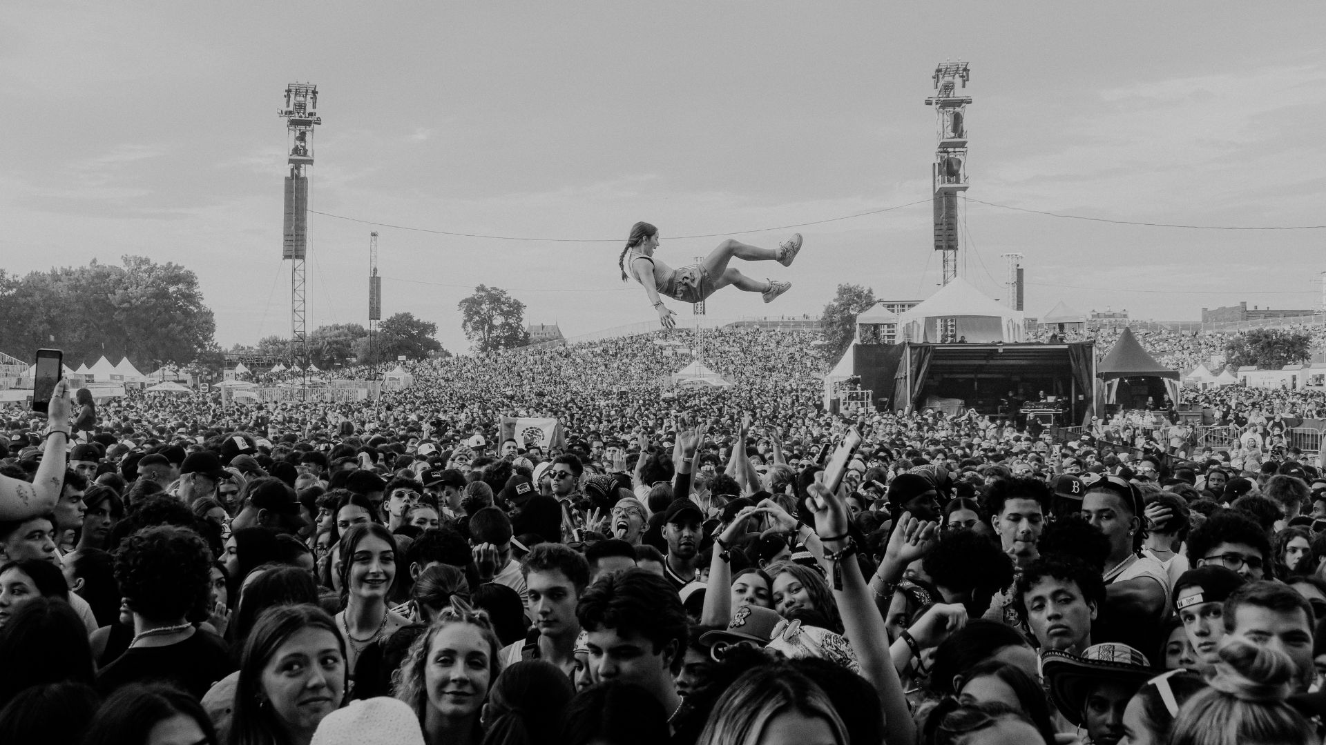 an image of a crowd at a festival festival, focusing on the centre where a fan watching has been thrown high up into the hair above the others
