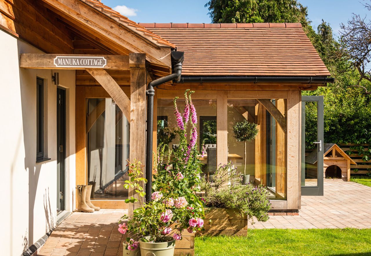 A contemporary oak frame extension leading onto a patio where fox gloves and flowers are growing