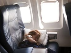 A young girl sleeps comfortable in an airplane seat.