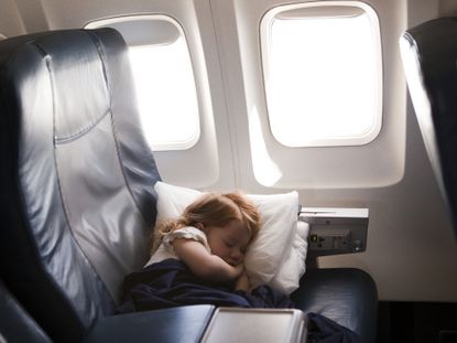 A young girl sleeps comfortable in an airplane seat.