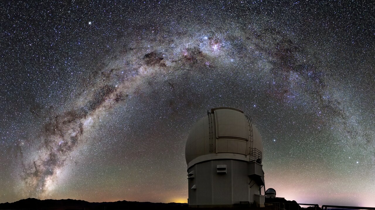 Dome-shaped observatory under an arc of bright stars against a dark sky