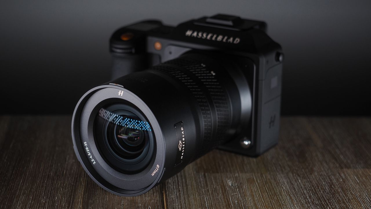 Hasselblad XCD 20-35E lens, moodily lit with subdued lighting, on a wooden surface