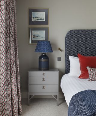 An example of bedroom curtain ideas showing a Moroccan-style blue and red patterned curtain, a blue bed, and matching scatter cushions