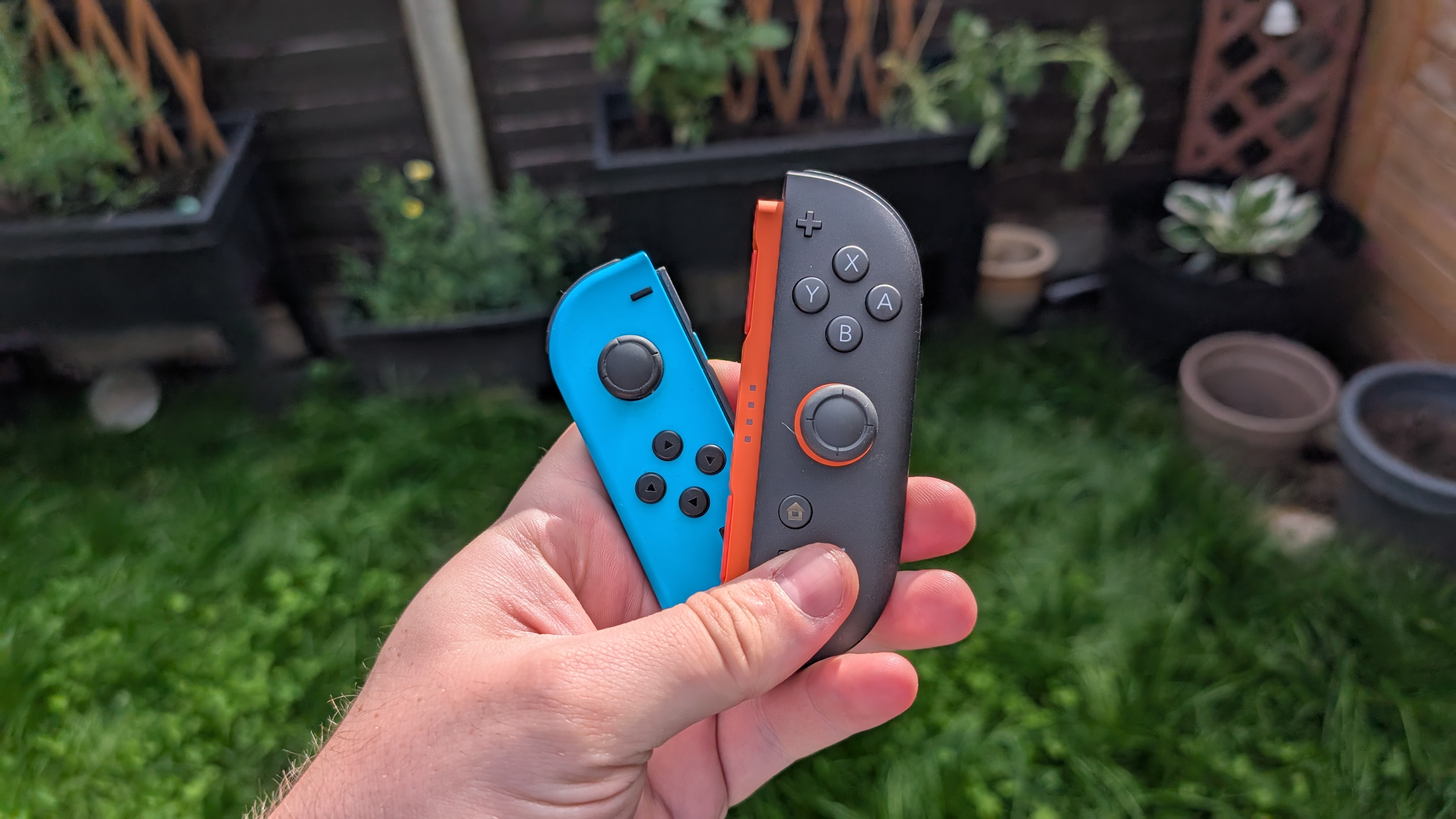 Nintendo switch joy-cons next to nintendo switch 2 joy-cons in the garden