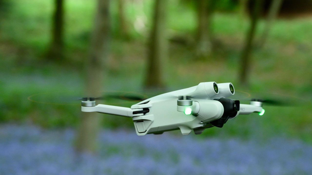 DJI Mini 3 Pro drone flying in a field of bluebells