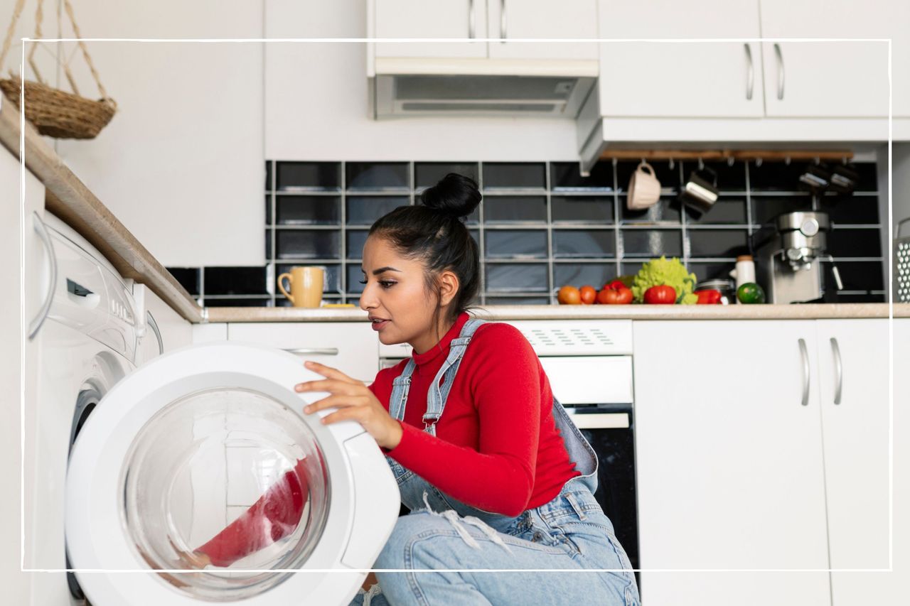 woman crouching down on floor in kitchen to load washing machine