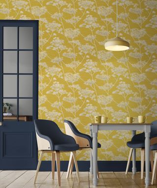 Yellow patterned kitchen wall with gray table and chairs in front.