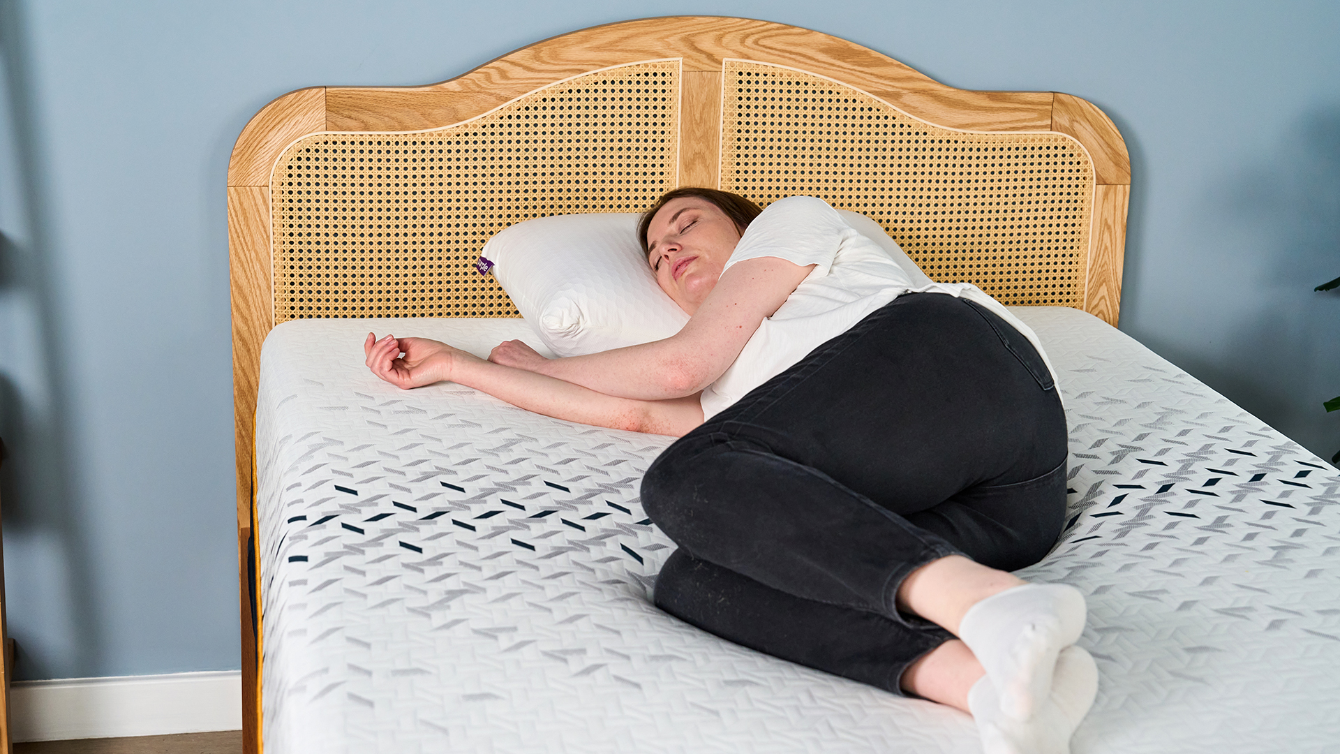 A female Tom's Guide mattress tester lying on her side on the Nectar Ultra Hybrid mattress