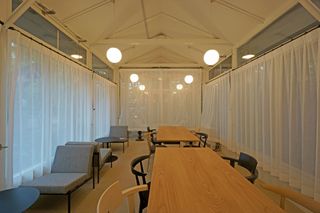 Alternative view of the Karuizawa workspace interior with hanging sphere lights and white curtains at the windows