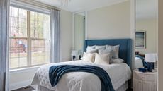Modern guest bedroom ideas are so pretty. Here is a white and blue bedroom with a blue bed with white bedding and a blue throw, and a large window