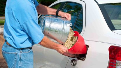A man pouring a bucket of cash into a gas tank