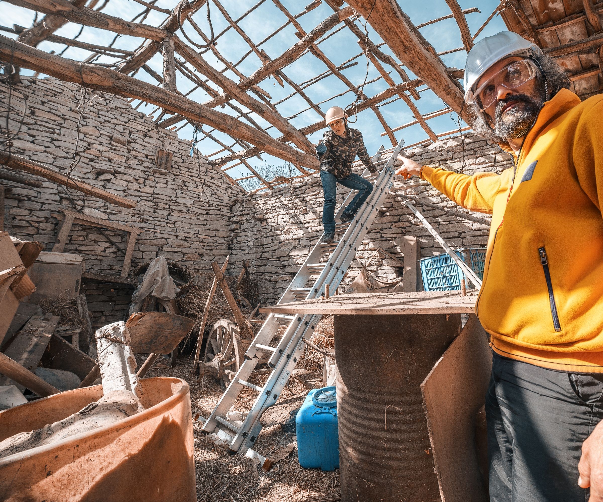 A barn conversion with no roof and a man in a yellow jacket doing construction work