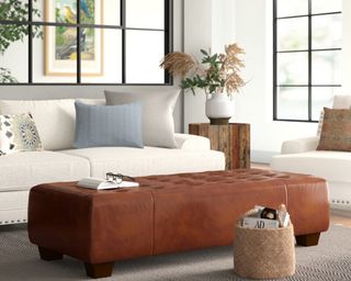 A long, soft brown coffee table ottoman in living room with cream sofa