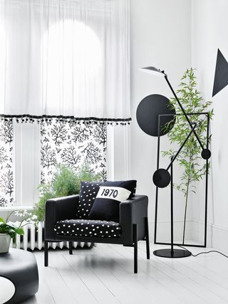 A white living room with a black sofa, black lights and curtains with black lining