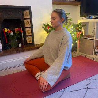 Woman wearing red leggings, white socks and grey sweater practicing yoga