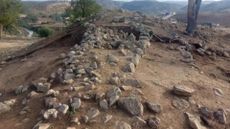 A pile of rocks in a row sit on a hill.