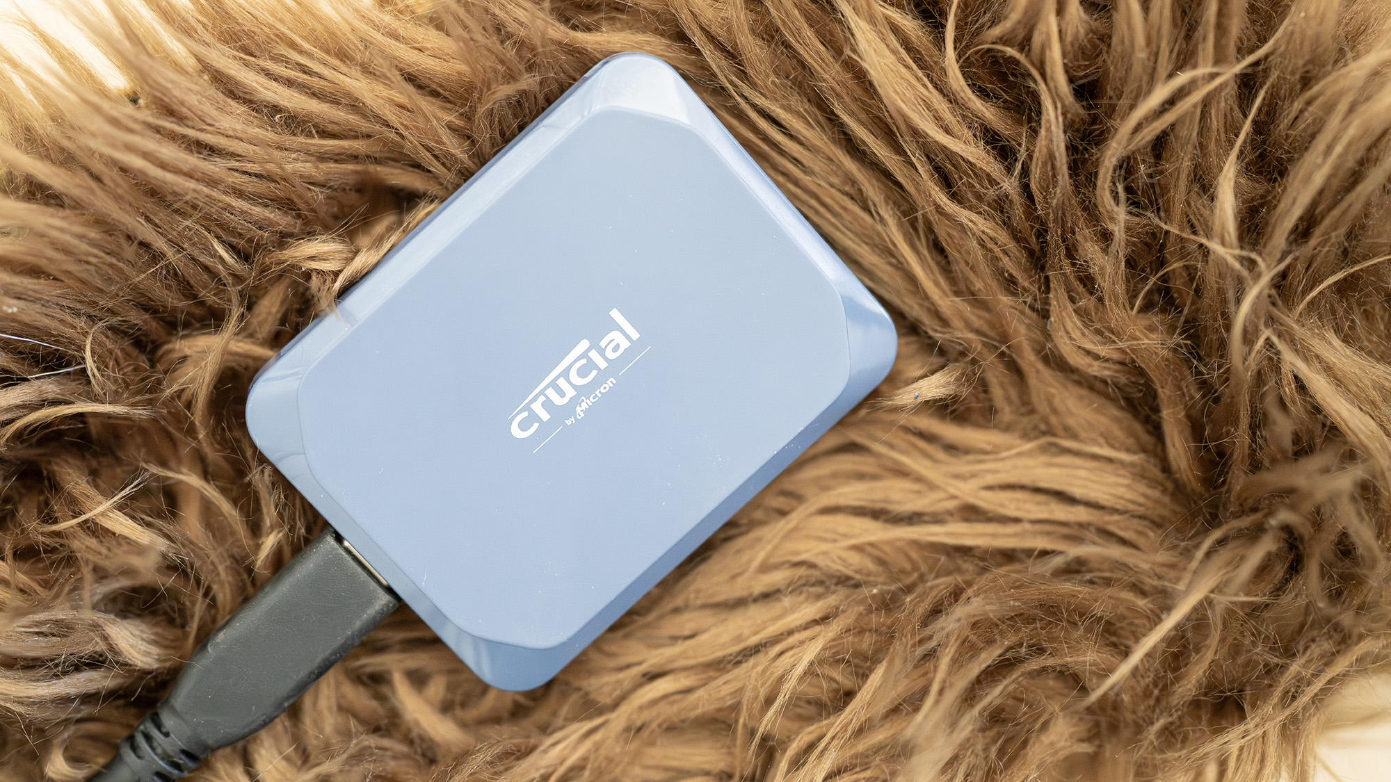 A Crucial X10 external SSD in blue with USB Type-C connector cable.