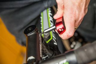 Image shows a torque wrench being used to tightened the stem bolts on a road bike stem