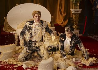 Prince Henry (Nicholas Galitzine) and Alex Claremont-Diaz (Taylor Zakhar Perez), covered in royal wedding cake, in Red, White, & Royal Blue.