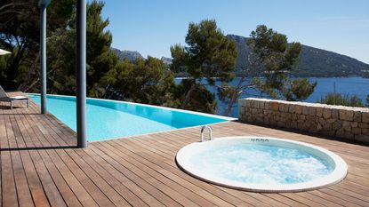 hot tub integrated in a wooden deck next to a pool