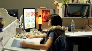 A woman sketching cartoon characters using a tablet while looking at a second monitor