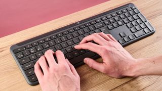 Hands typing on the Logitech Signature Slim K950