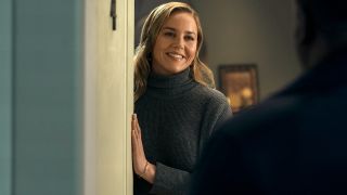 Abbie Cornish smiling as she leans against an open door in Tom Clancy's Jack Ryan.