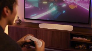 Sonos Ray in living room with man playing PS5