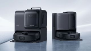 The Eufy Omni E25 and E28 robot vacuums sitting in their docks on a grey marble floor against a light background.