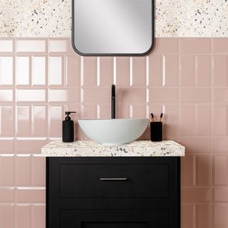 An under stairs bathroom with pink tiles and a mosaic worktop