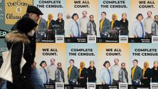People walk past posters encouraging participation in the 2020 Census