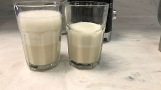 smeg milk frother behind two glasses of frothed oat milk